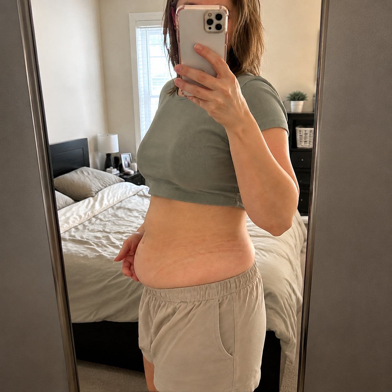 Woman looking at her postpartum belly in the mirror